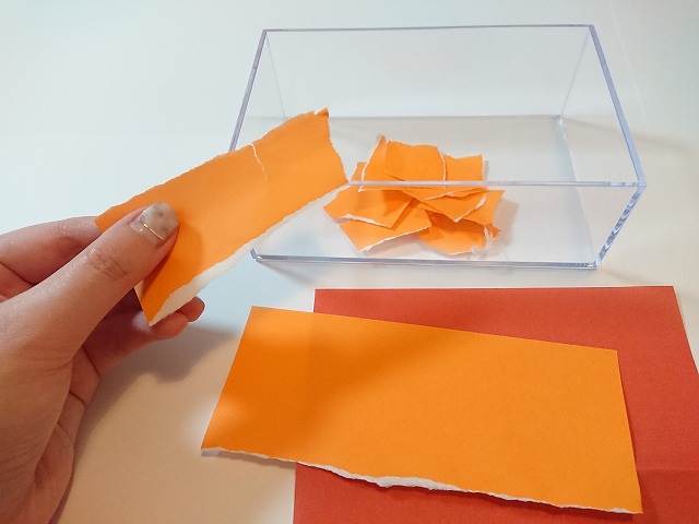 オレンジ色の折り紙をちぎる