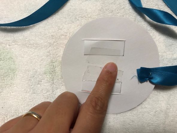 王冠をメダルに差し込み、テープでとめる