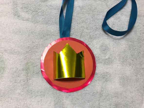 王冠をメダルに差し込み、テープでとめる